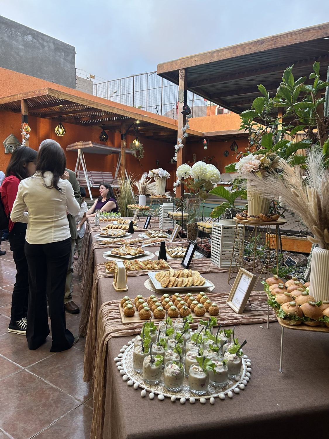 Invitados recorriendo una gran mesa de banquetería al aire libre